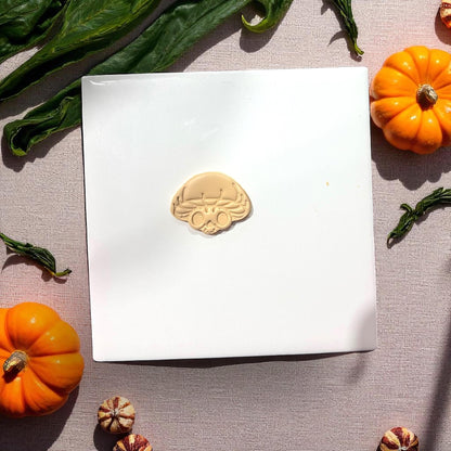 Mushroom skull clay shape on white tile with pumpkins