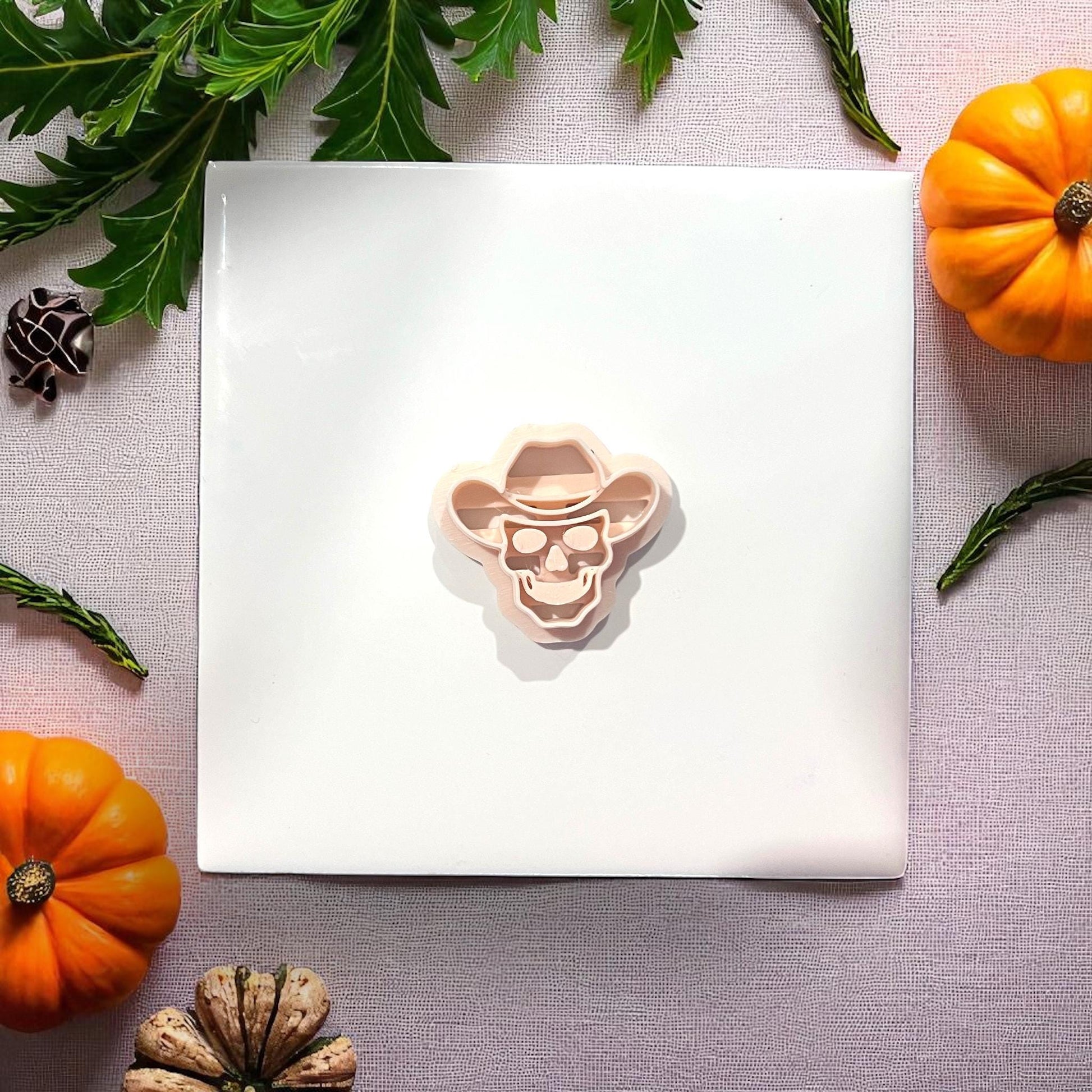 Cowboy skull clay cutter on white tile with pumpkins