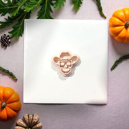 Cowboy skull clay cutter on white tile with pumpkins