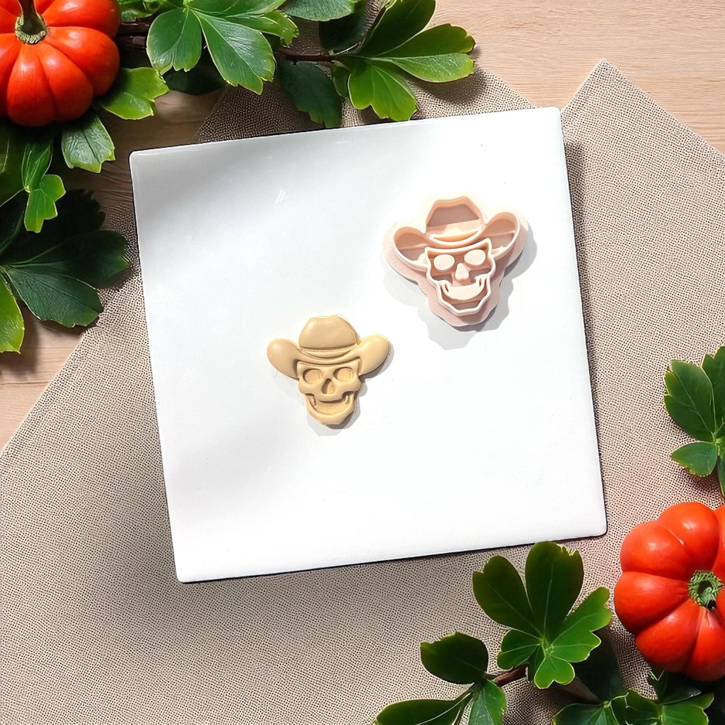 Cowboy skull cutter with clay piece on white tile with greenery
