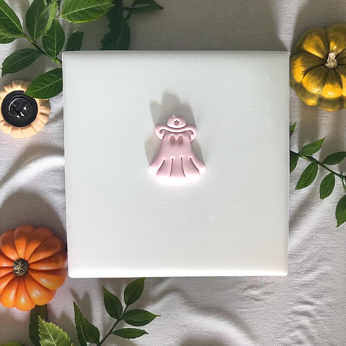 Cowboy ghost clay shape on tile with greenery and pumpkins