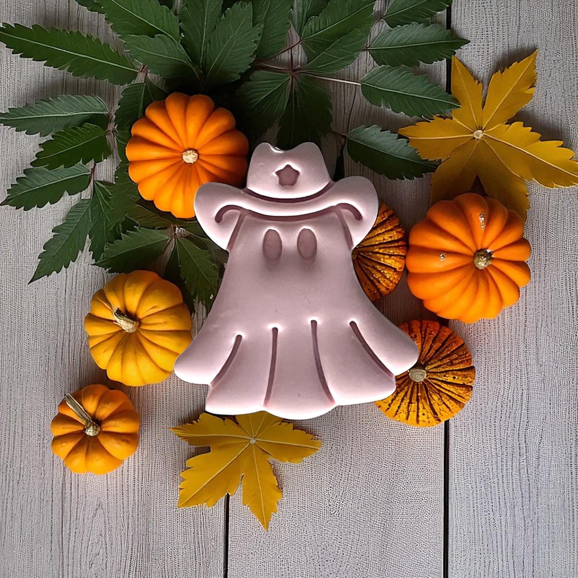 Cowboy ghost clay piece surrounded by pumpkins and leaves