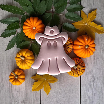Cowboy ghost clay piece surrounded by pumpkins and leaves