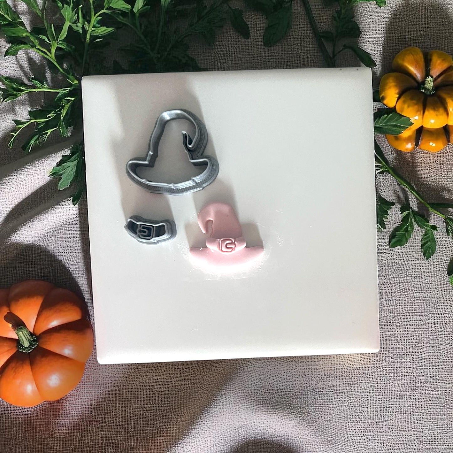 Pink clay witch hat with buckle on round wooden board