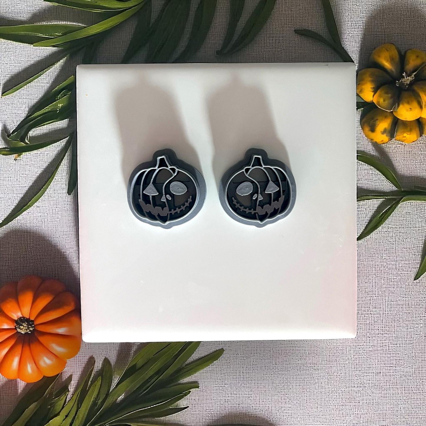 Pumpkin skull clay cutters on white tile with pumpkins and leaves