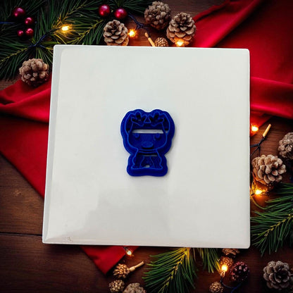 Blue dog with reindeer ears cutter on white tile with pinecones and Christmas lights