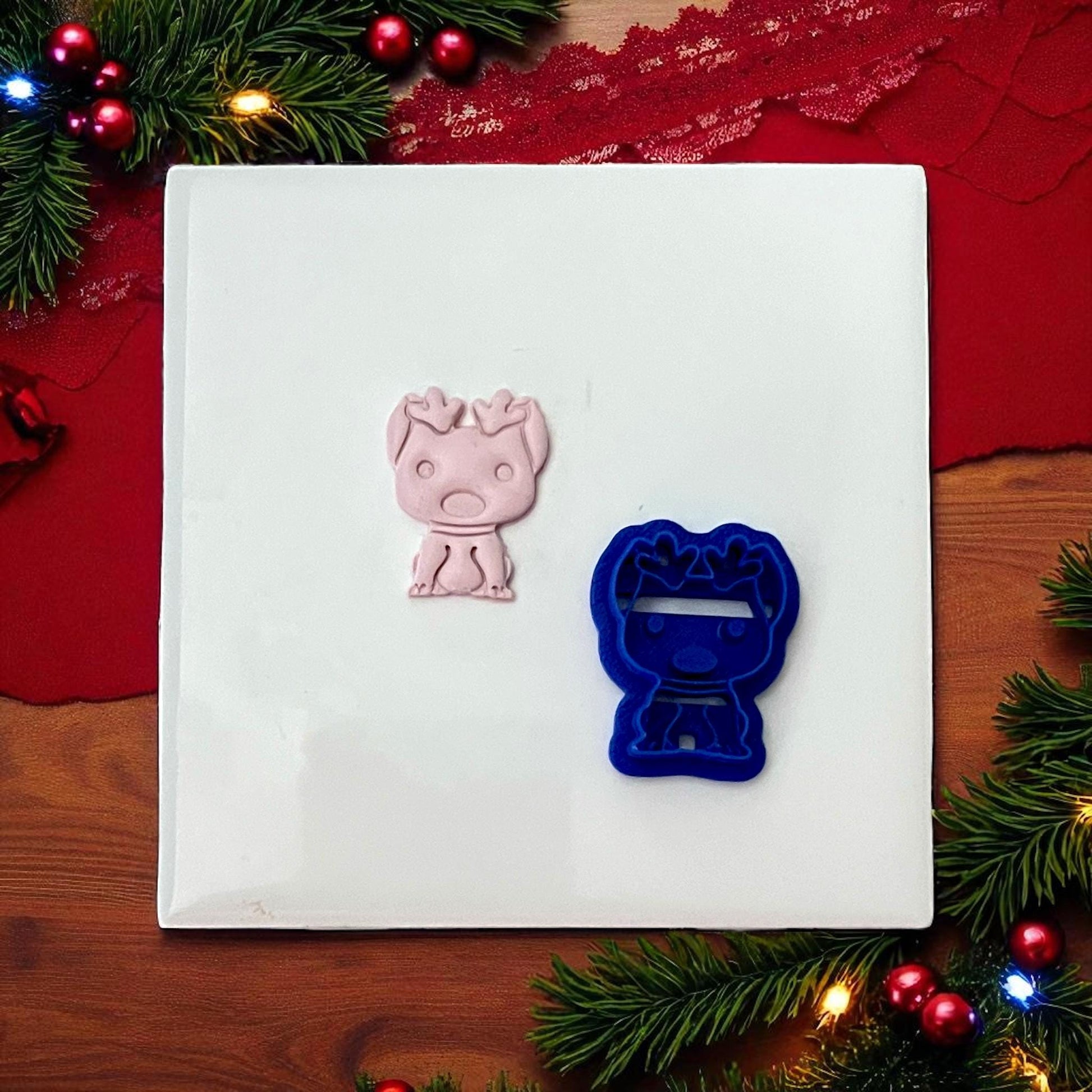 Blue dog with reindeer ears cutter and pink imprint side by side on white tile
