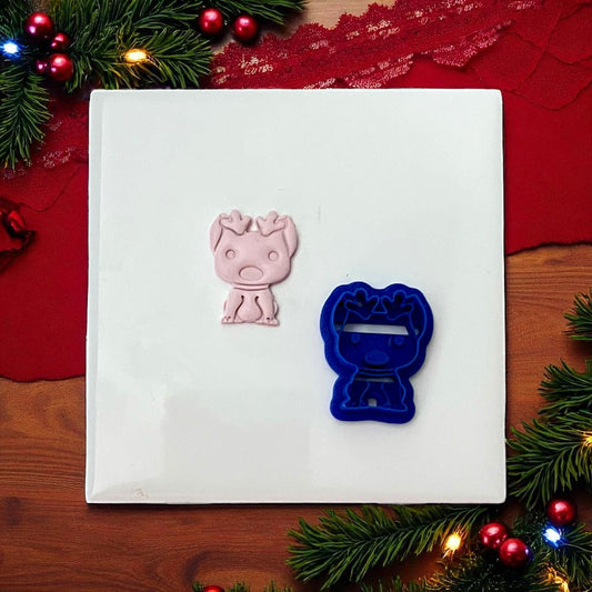 Blue dog with reindeer ears cutter and pink imprint side by side on white tile