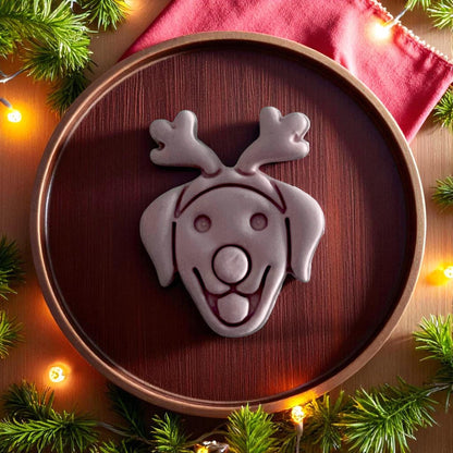 Large clay imprint of labrador with reindeer nose and antlers on wooden plate with Christmas greenery