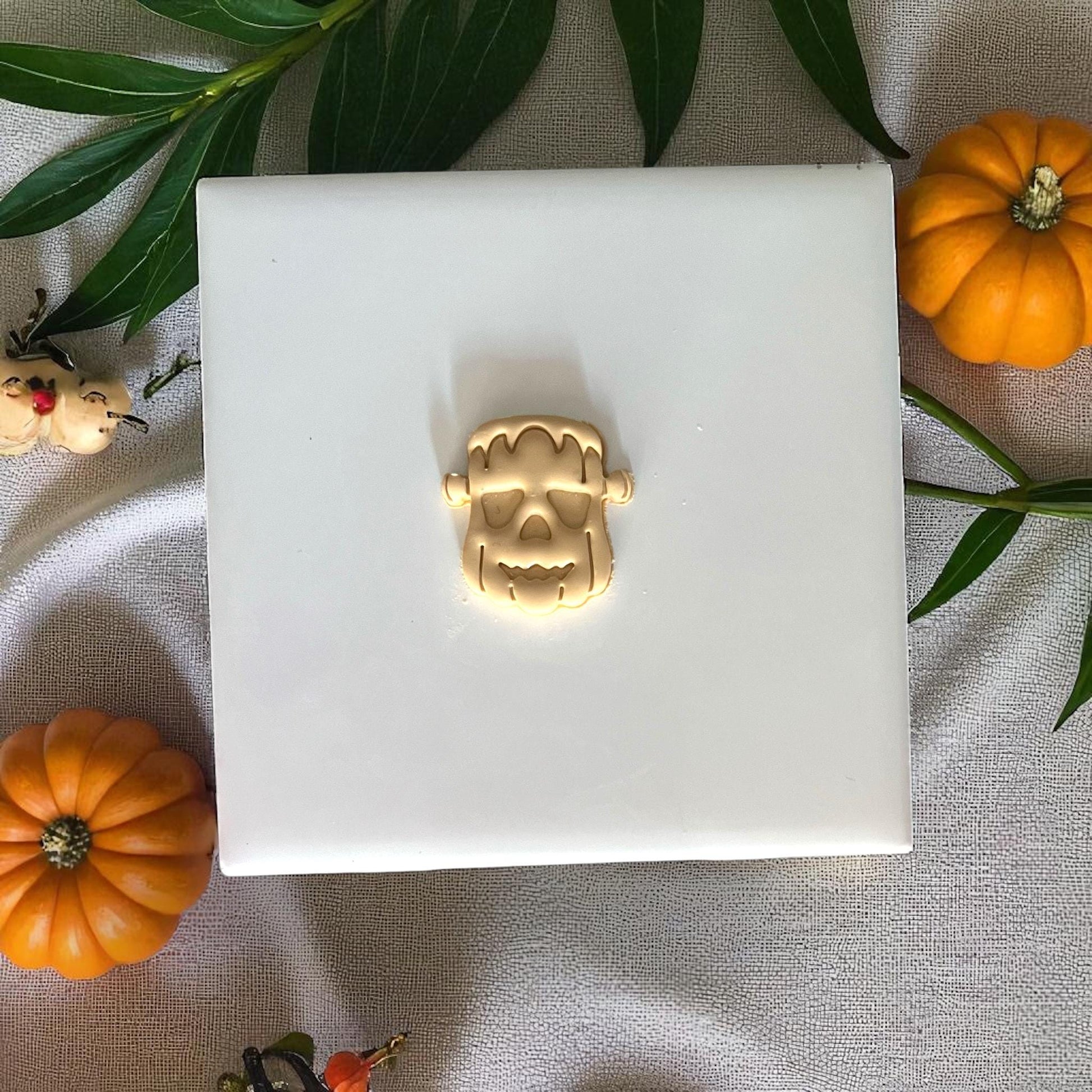 Small Frankenstein pumpkin clay imprint on white tile