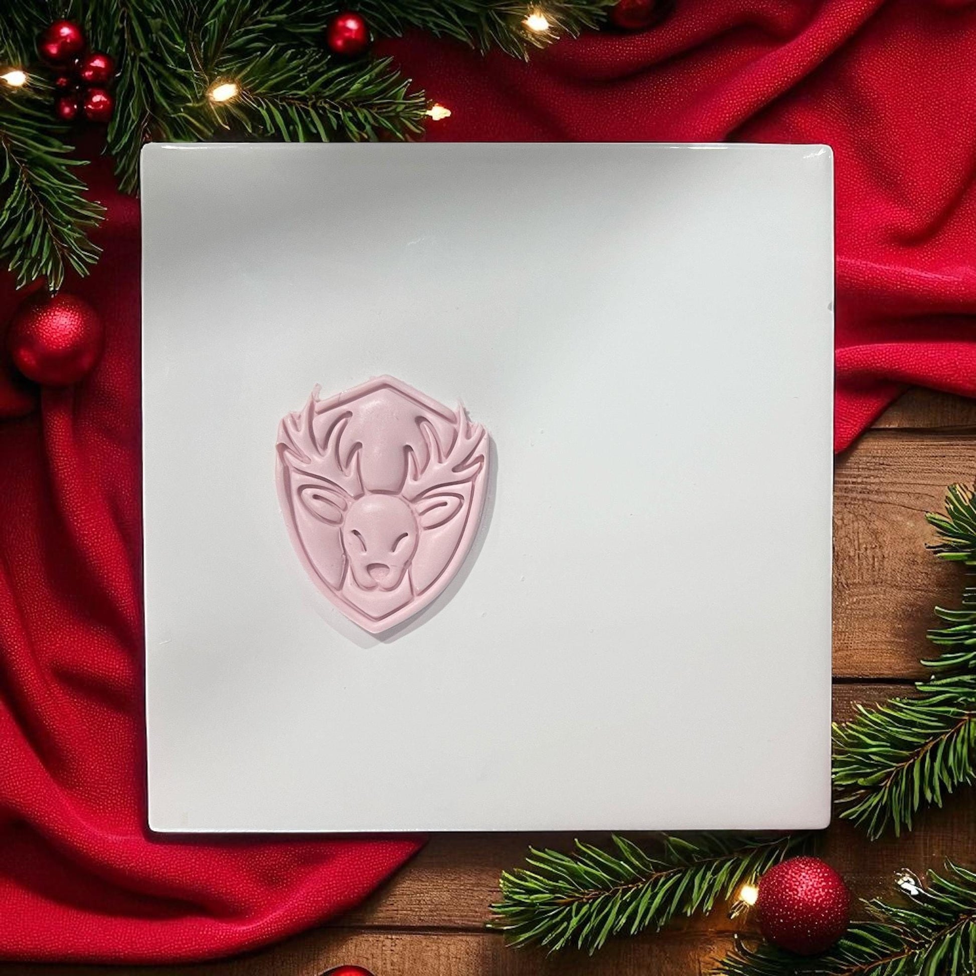 Reindeer clay imprint on white tile with holiday greenery