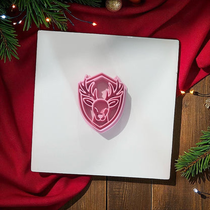 Pink reindeer polymer clay cutter on white background with red fabric