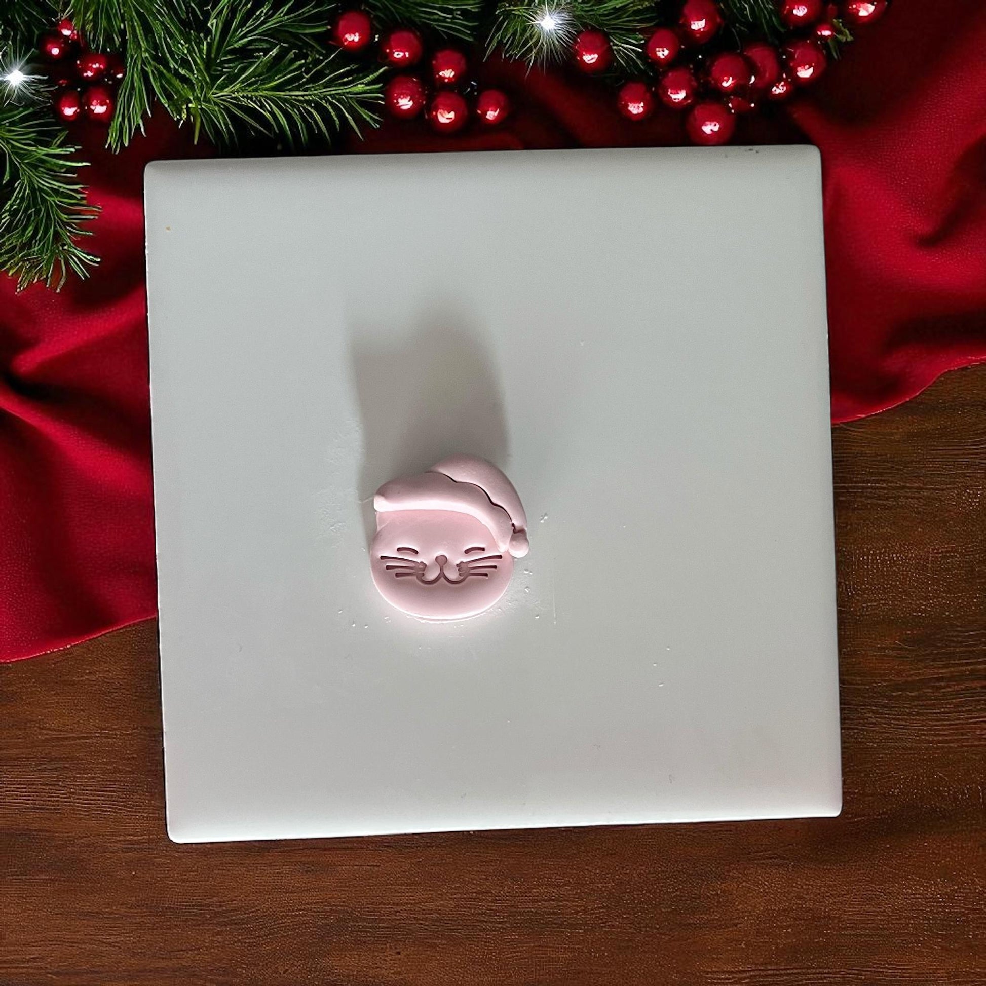 Small Santa cat clay imprint on white tile with Christmas decor