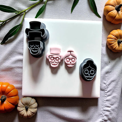 Skull couple clay cutters with clay impressions surrounded by pumpkins
