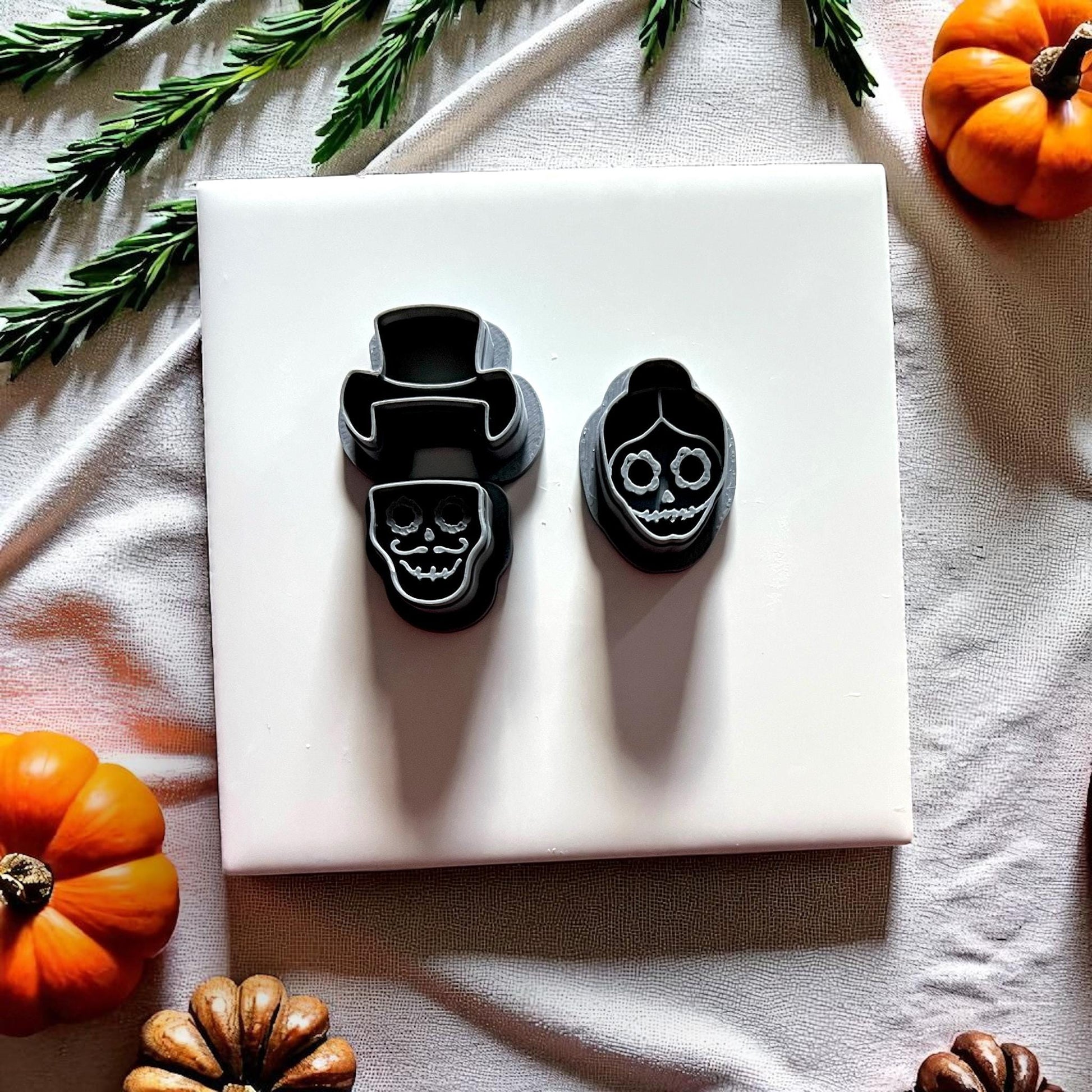 Skull couple clay cutters in black with pumpkins and greenery