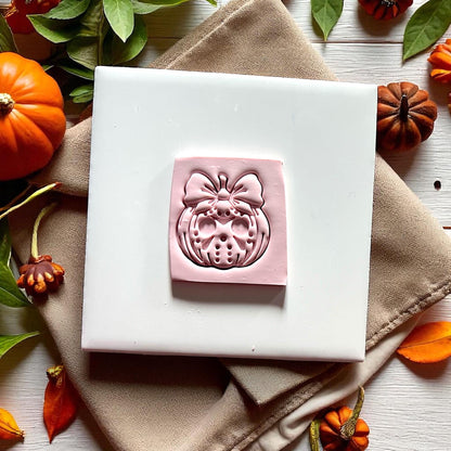 Jason pumpkin with bow clay imprint on pink clay with pumpkins