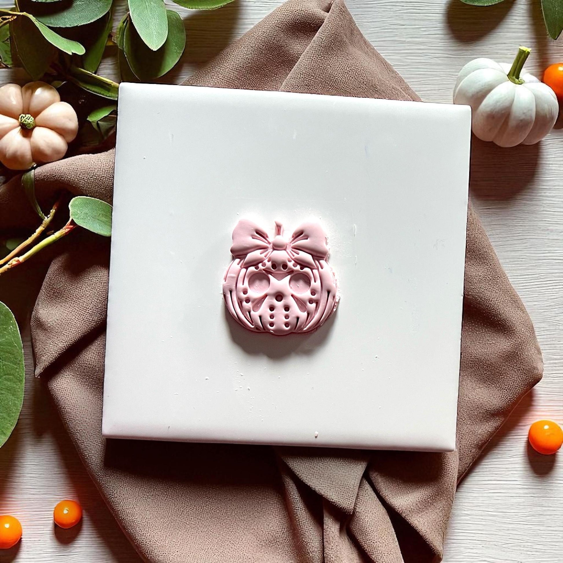 Finished Jason inspired pumpkin with bow in pink clay on white tile