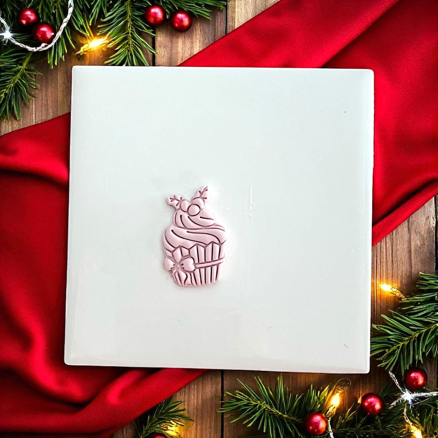 Holiday cupcake clay impression on white tile with red background