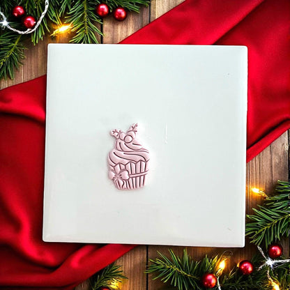 Holiday cupcake clay impression on white tile with red background