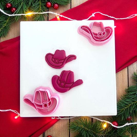 Mr and Mrs Santa cowboy hat polymer clay cutters in pink on white tile with red background