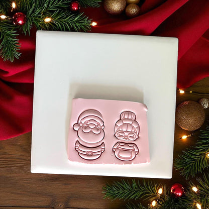 Santa and Mrs Claus clay cutter imprint in pink clay on white tile with Christmas decor
