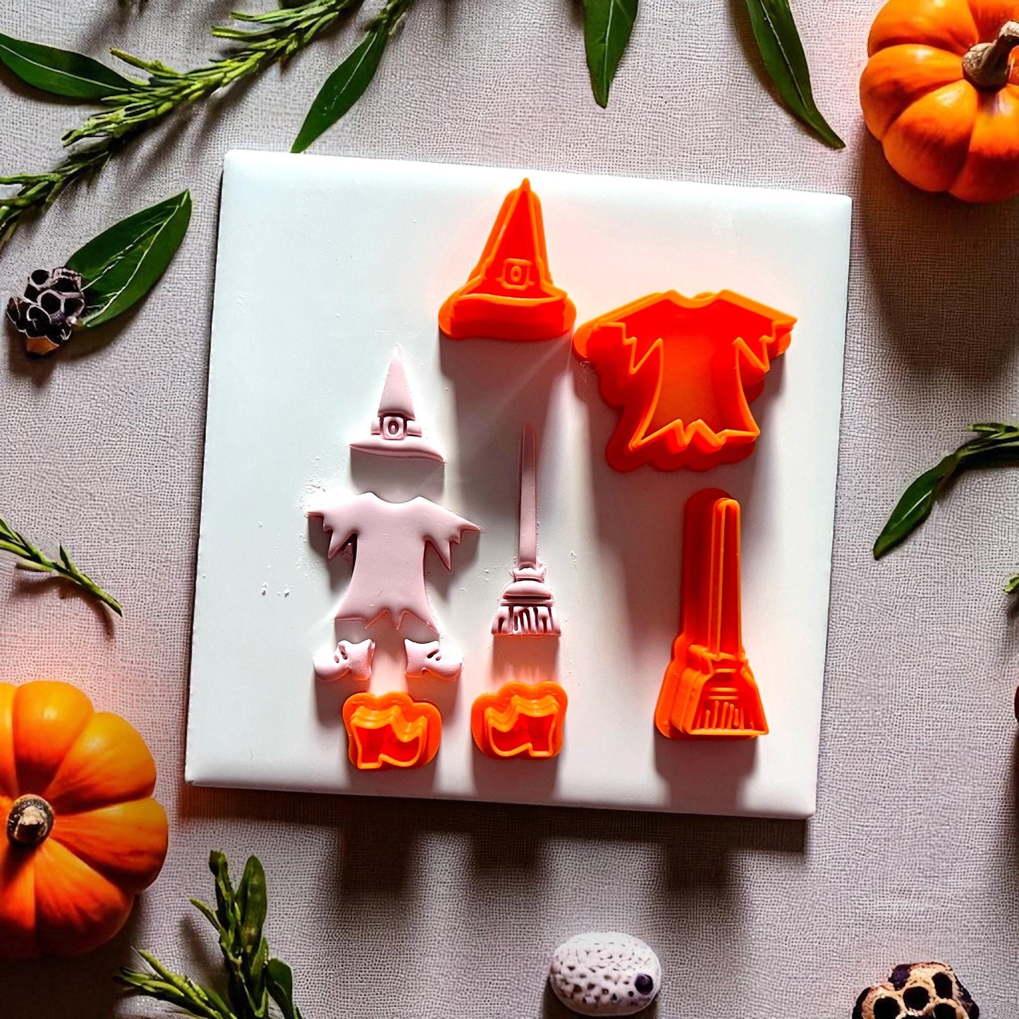 Witch cutter set with orange cutters and pink clay impressions on white background