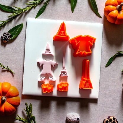 Witch cutter set with orange cutters and pink clay impressions on white background