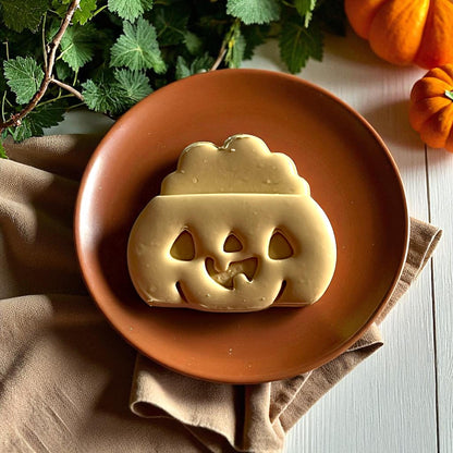 Large jack o lantern clay cutout with smiling pumpkin face on brown plate