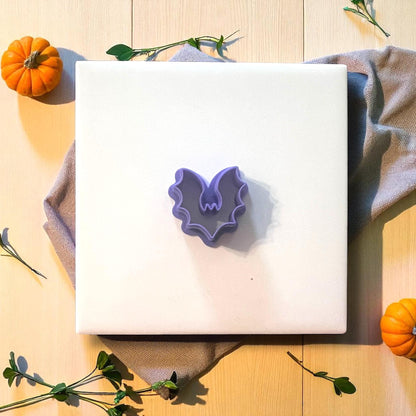 Purple bat clay cutter on white tile with fabric and pumpkins