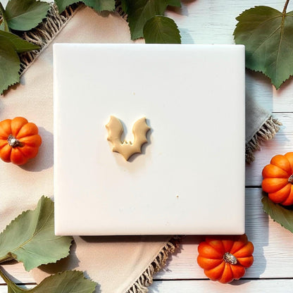 Small bat clay imprint on white tile with pumpkins and leaves