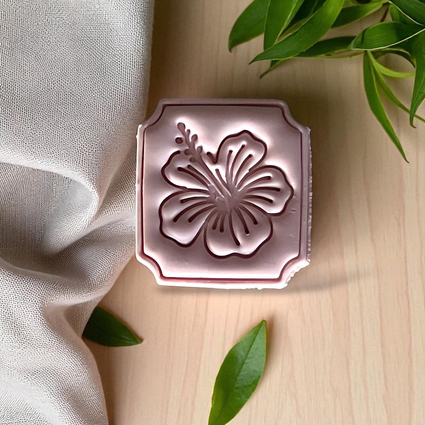 Hibiscus clay imprint framed in rectangle on white tile