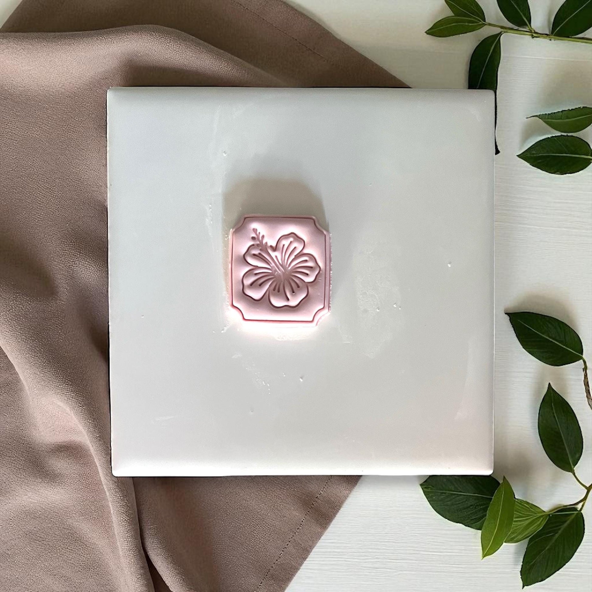 Hibiscus clay imprint with petals and stamen detail on wood surface