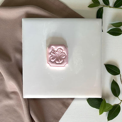 Hibiscus clay imprint with petals and stamen detail on wood surface