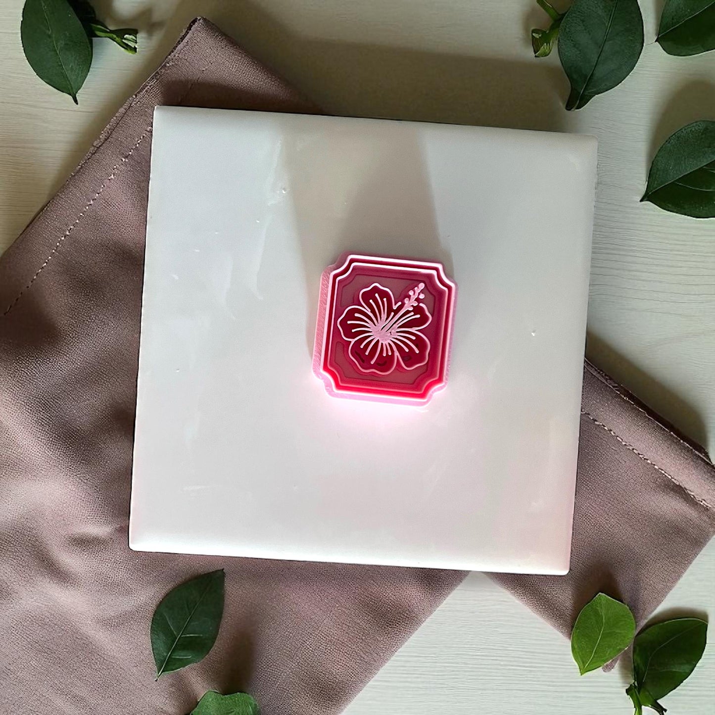 Hibiscus framed flower imprint in pink clay square on white tile