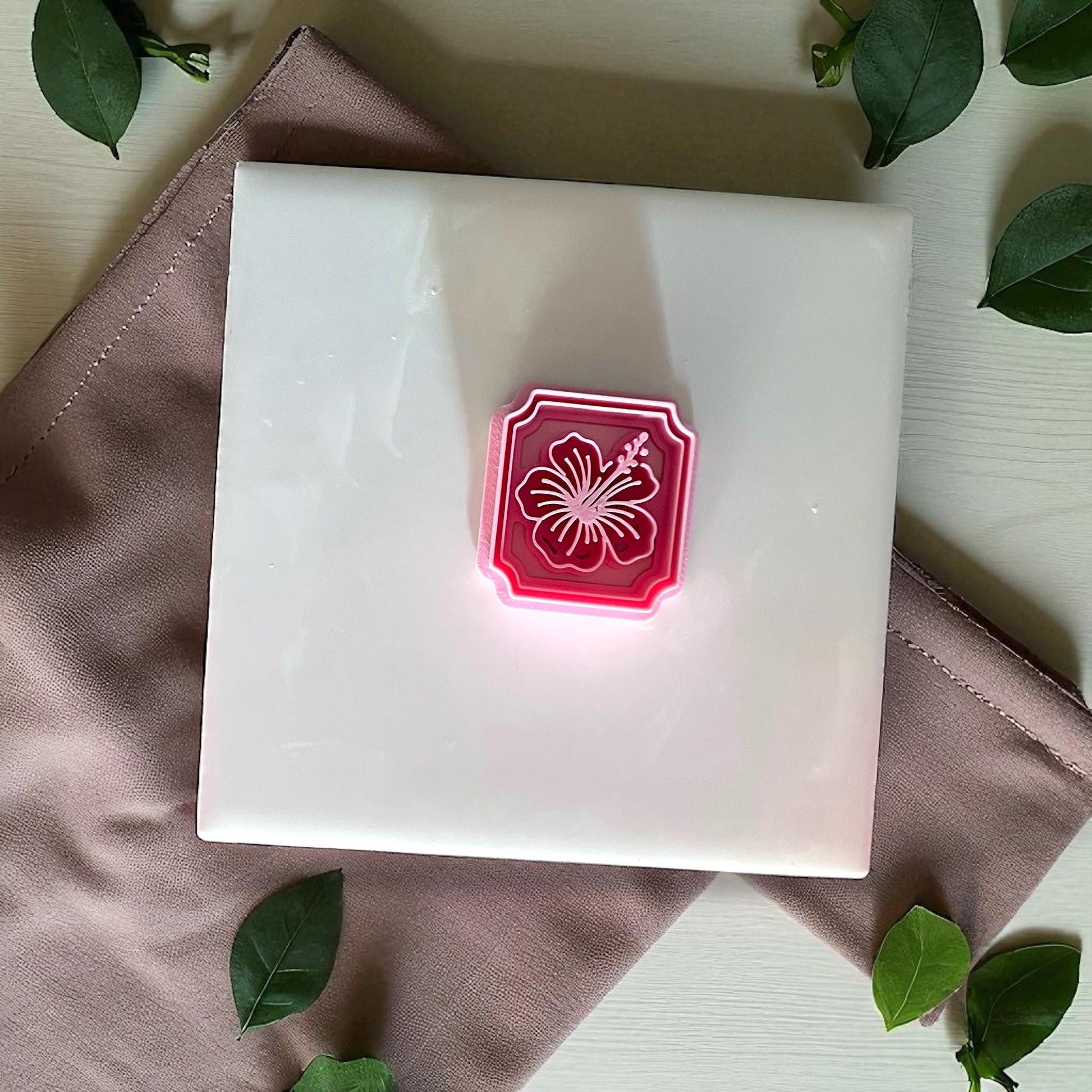 Hibiscus framed flower imprint in pink clay square on white tile