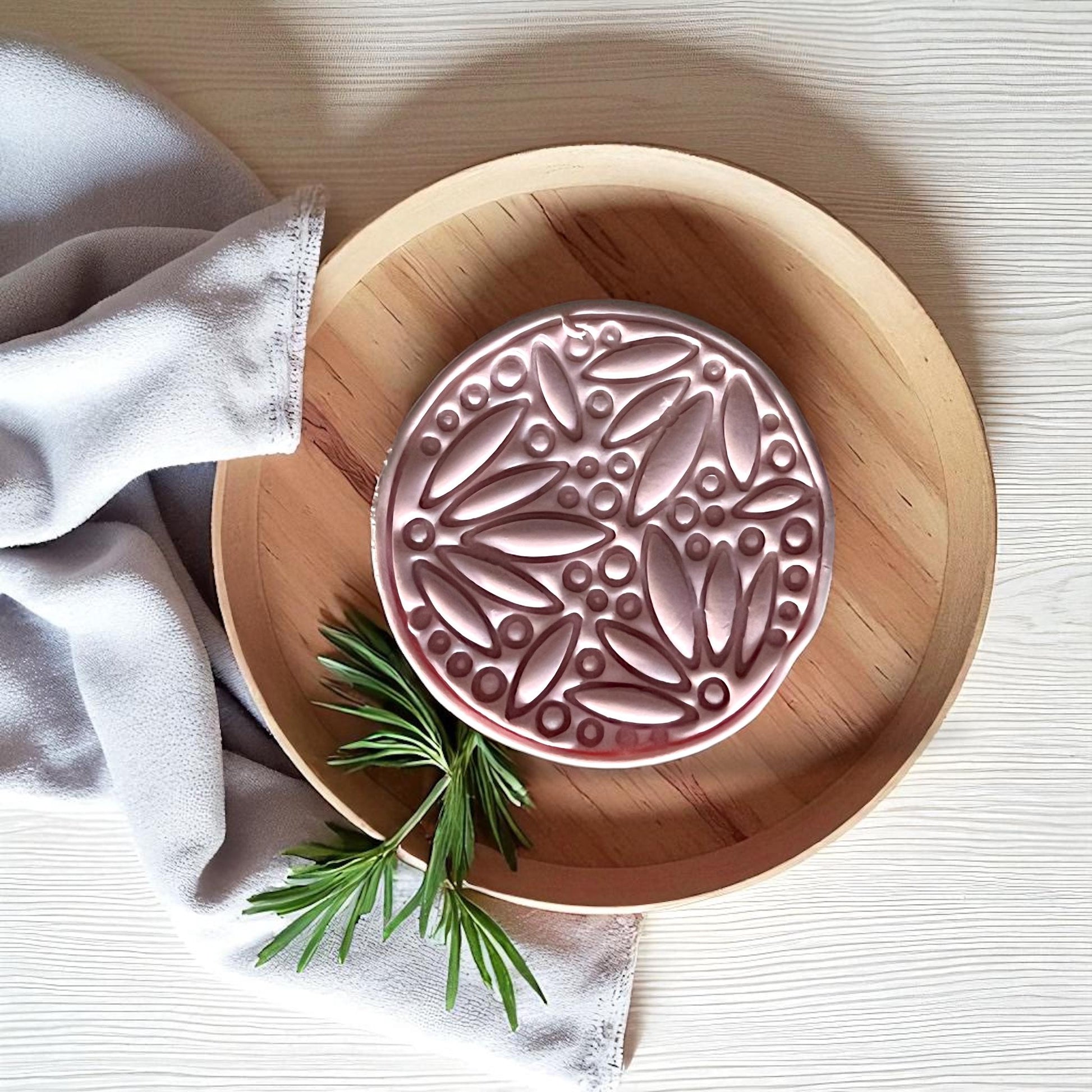 Round botanical clay imprint with leaves and berries on wood plate