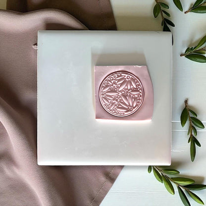 Leafy botanical clay imprint pressed into pink clay square
