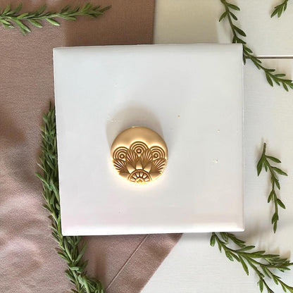 Round clay imprint with geometric Art Deco fan pattern