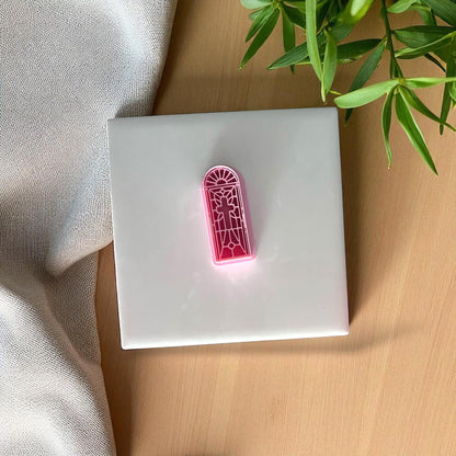 Pink stained glass cross polymer clay cutter on white tile