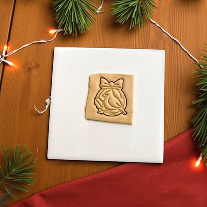 Christmas cardinal polymer clay impression with bow and wreath on tan clay
