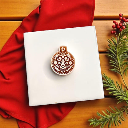 Nordic Christmas ornament cutter on red background surrounded by greenery