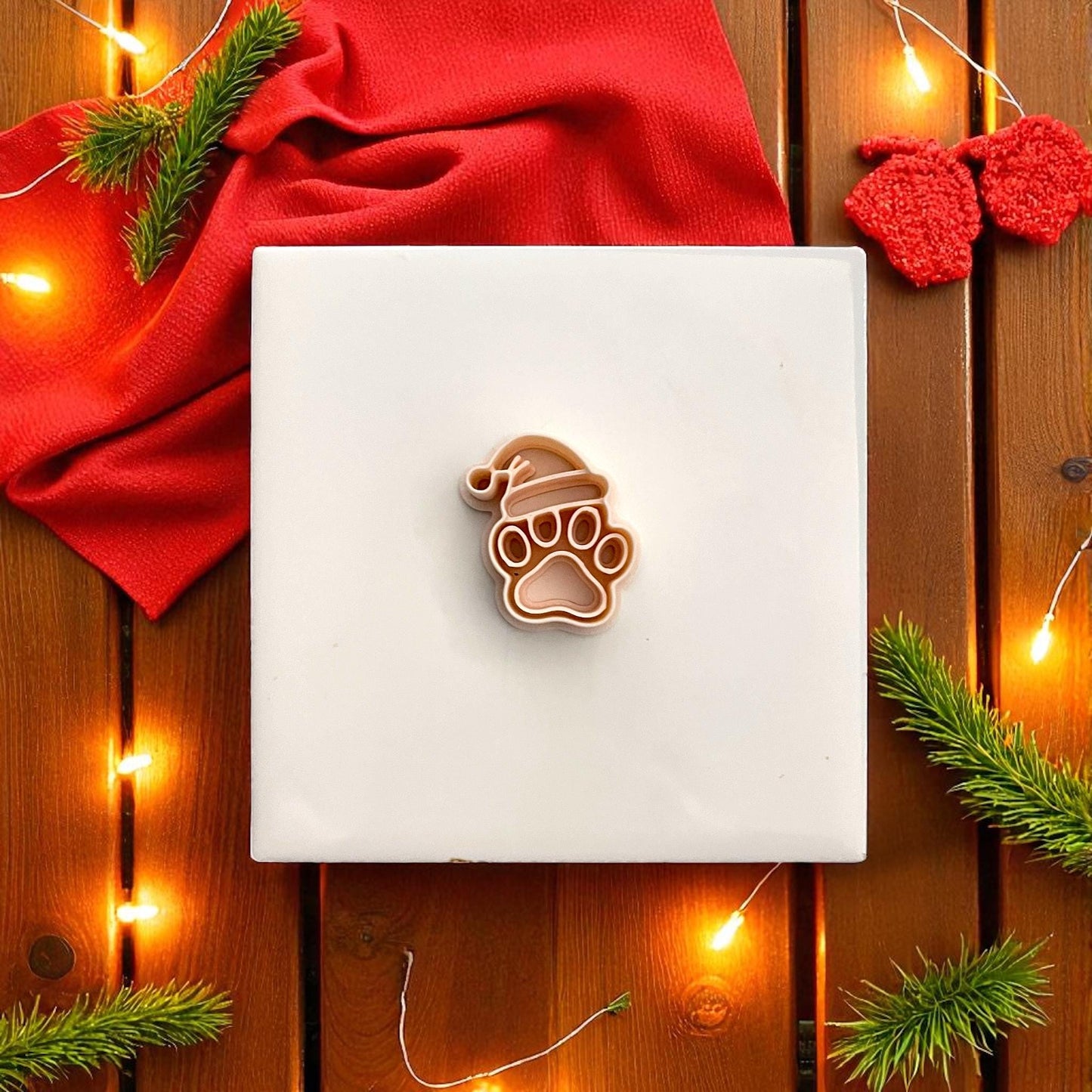 Christmas paw print polymer clay imprint with Santa hat on tan clay with festive lights