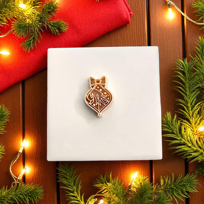 Polymer clay cutter shaped like Grinch hand ornament with bow surrounded by greenery