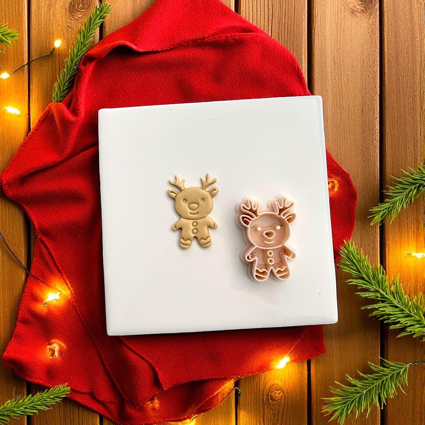 Gingerbread reindeer cutter and clay imprint side by side on white tile with red cloth