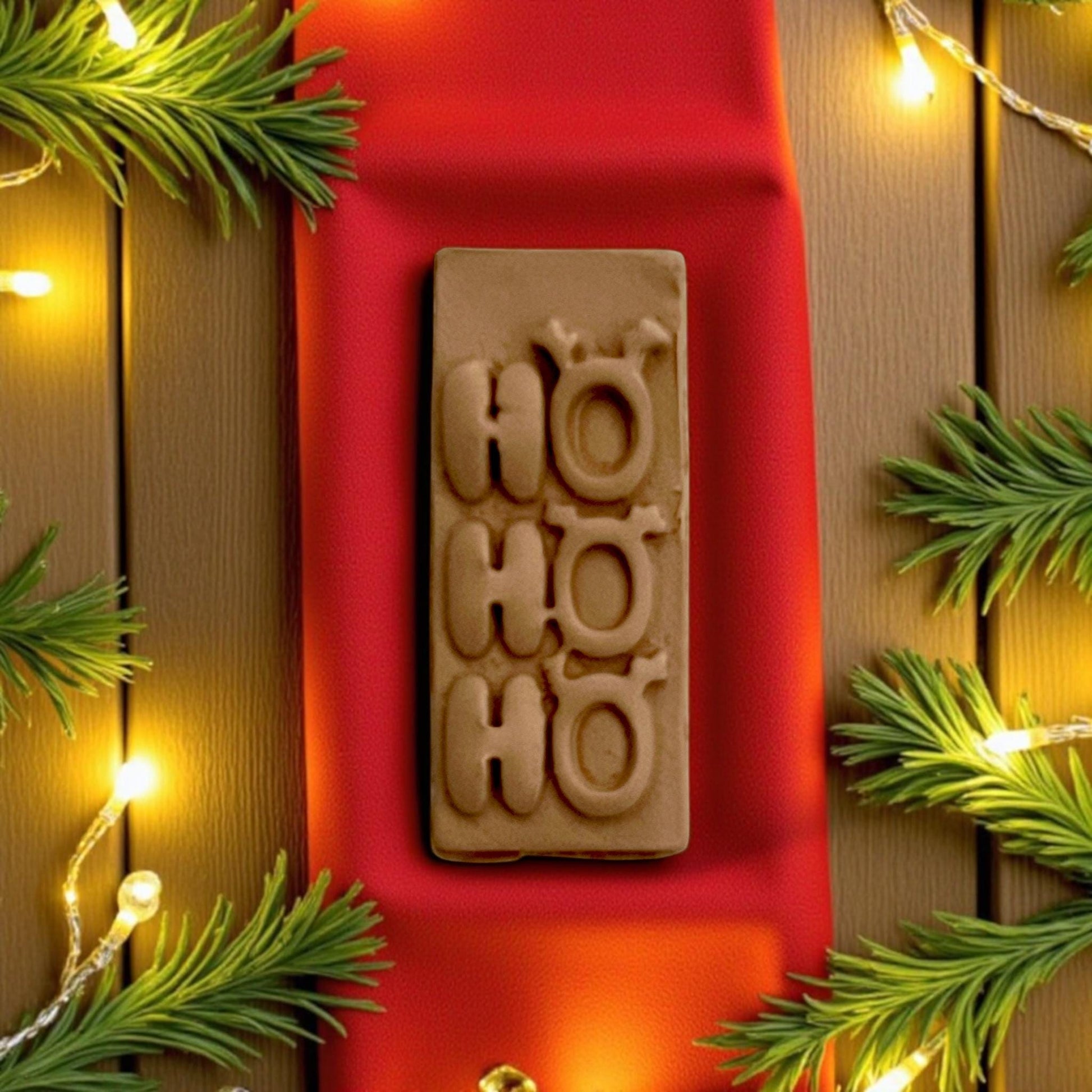 Vertical Ho Ho Ho imprint on red cloth surrounded by pine branches and string lights