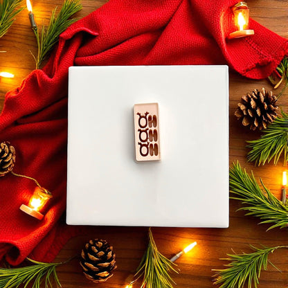 Polymer clay Ho Ho Ho cutter on white tile with red fabric and lights