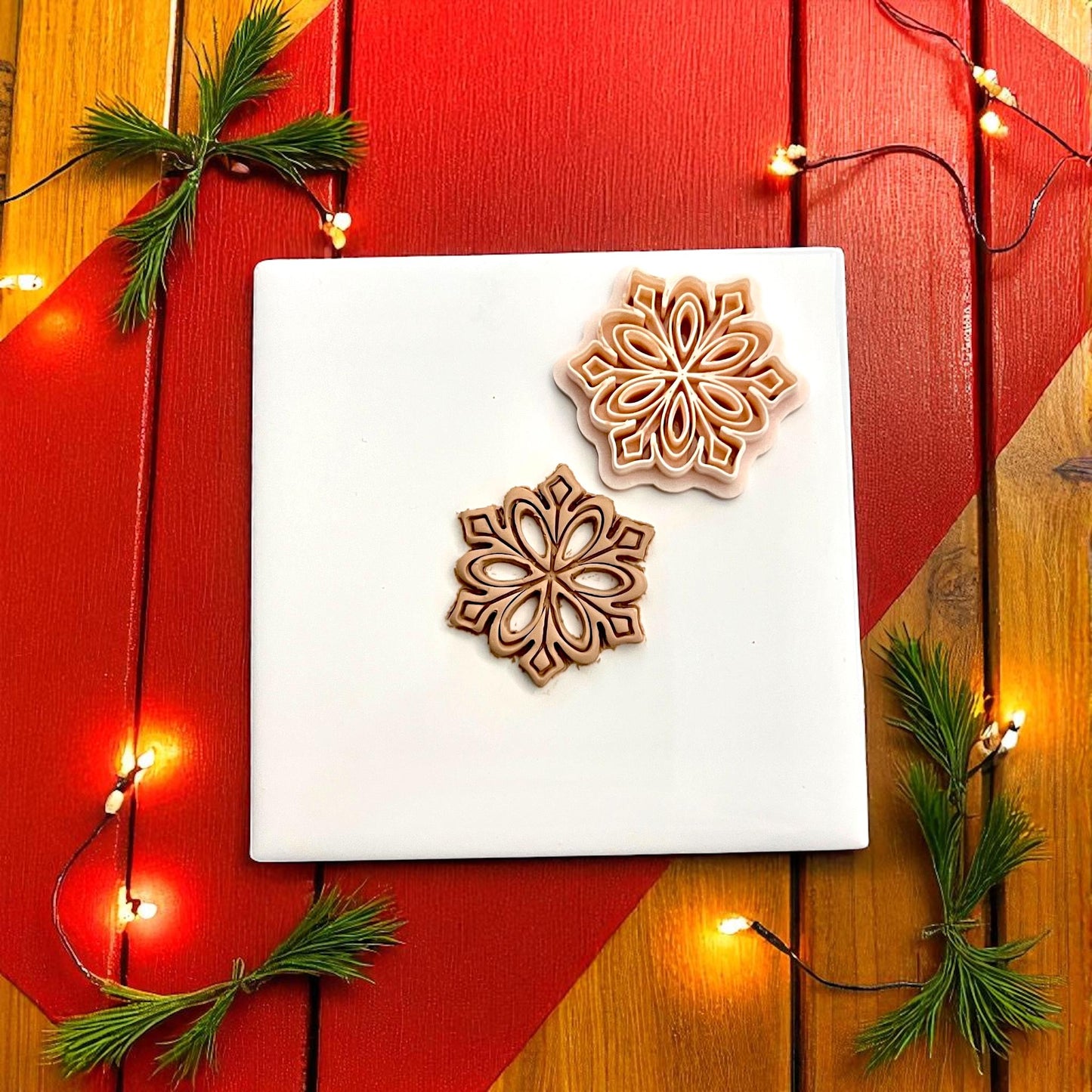 Snowflake cutter and imprint side by side on white tile with Christmas lights