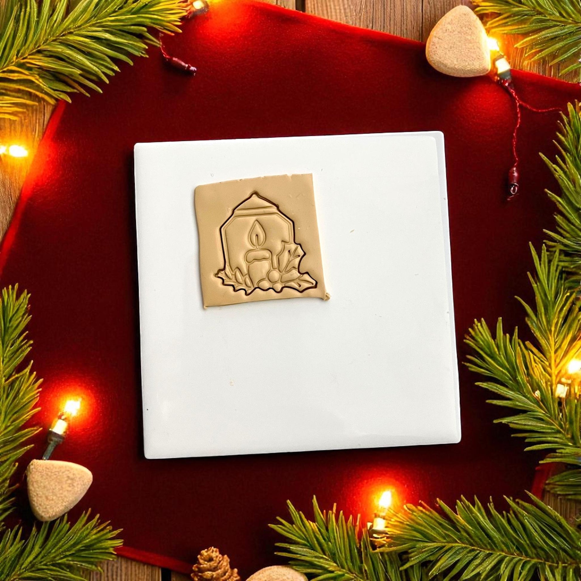 Large candle polymer clay imprint on red fabric with lights and greenery