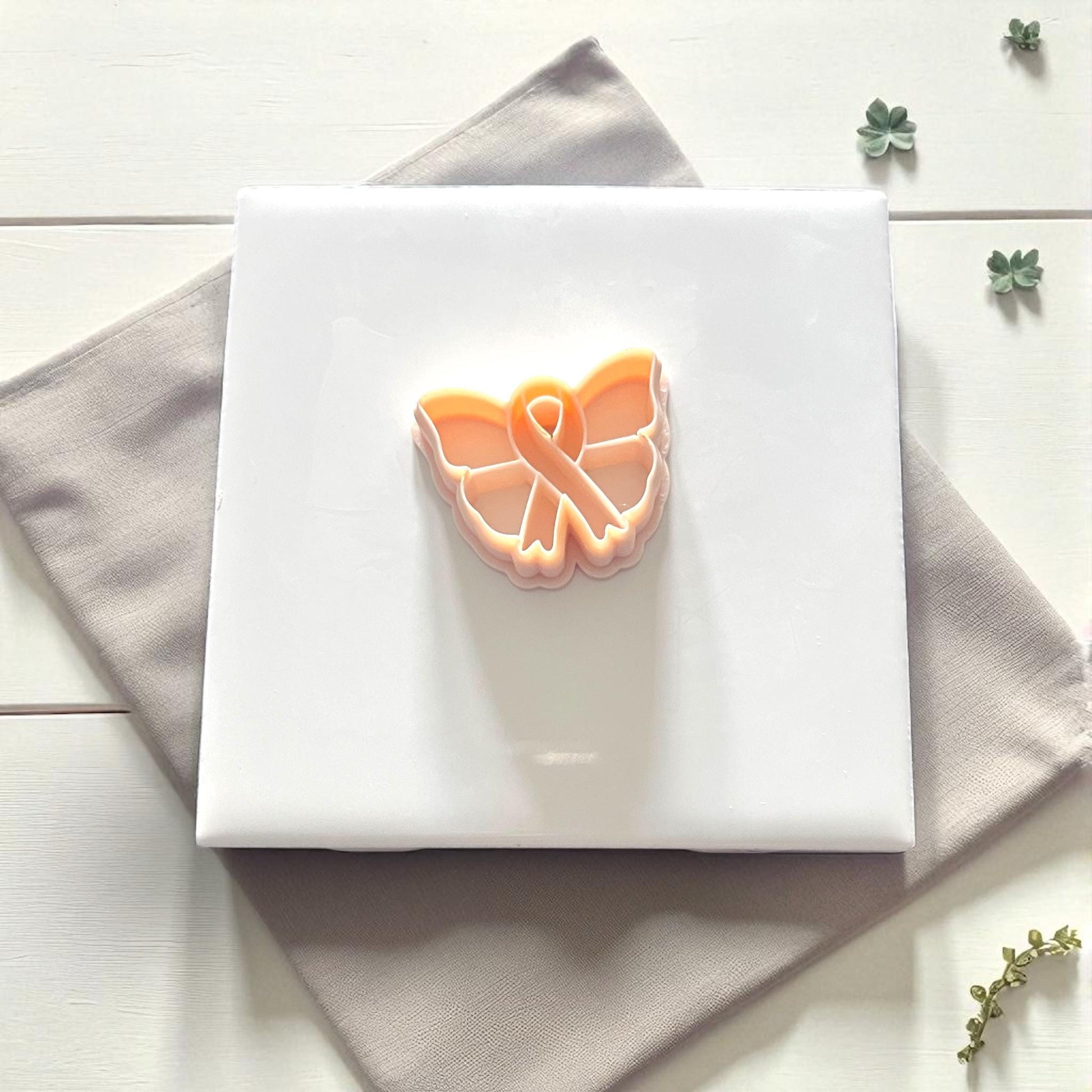 Close-up of butterfly ribbon clay impression surrounded by leaves