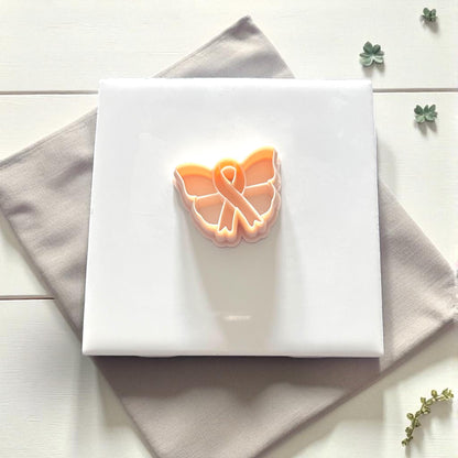 Close-up of butterfly ribbon clay impression surrounded by leaves